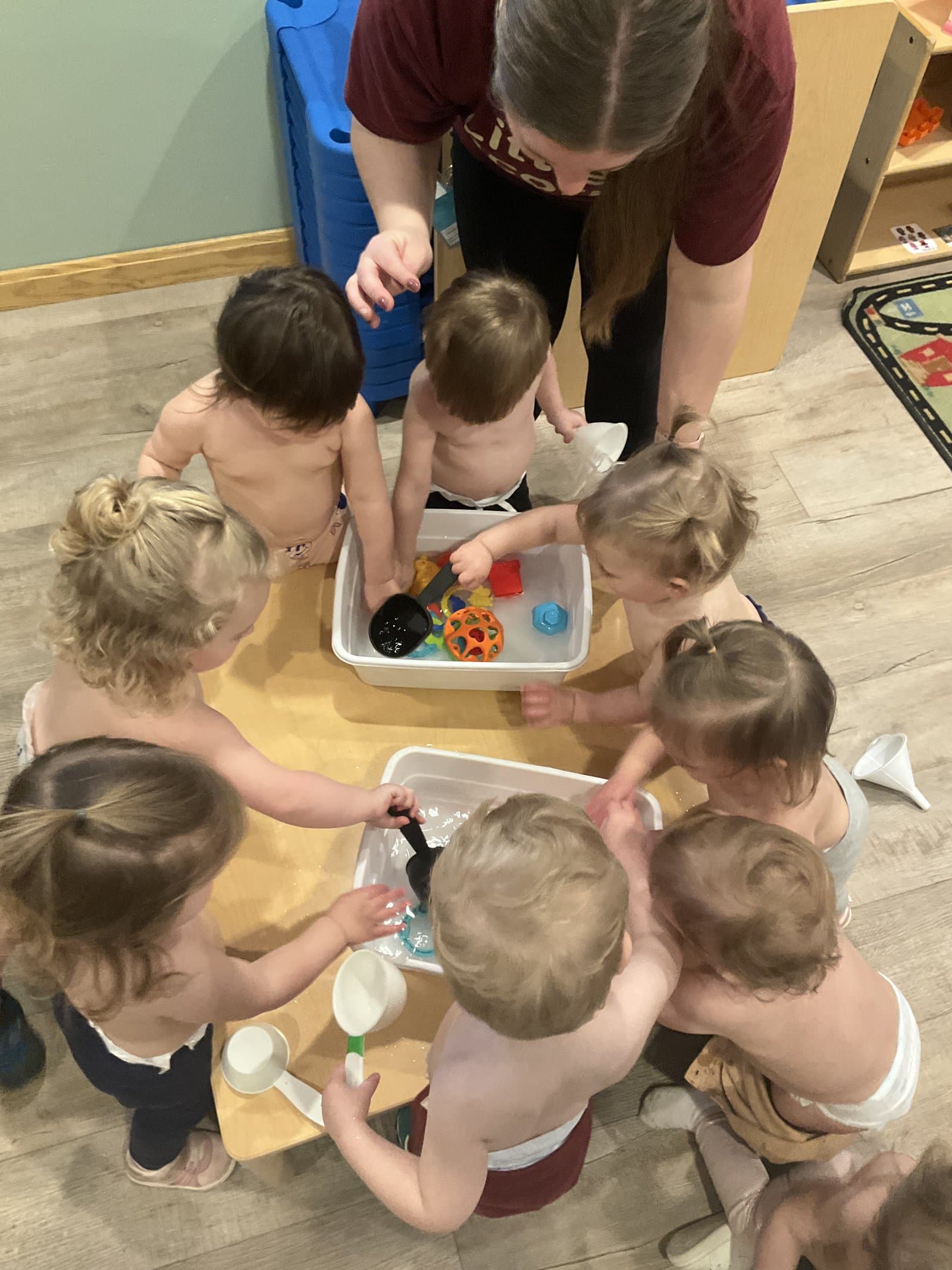 Toddlers at Little Acorns Learning Center exploring sensory play with their teacher in Erie, PA