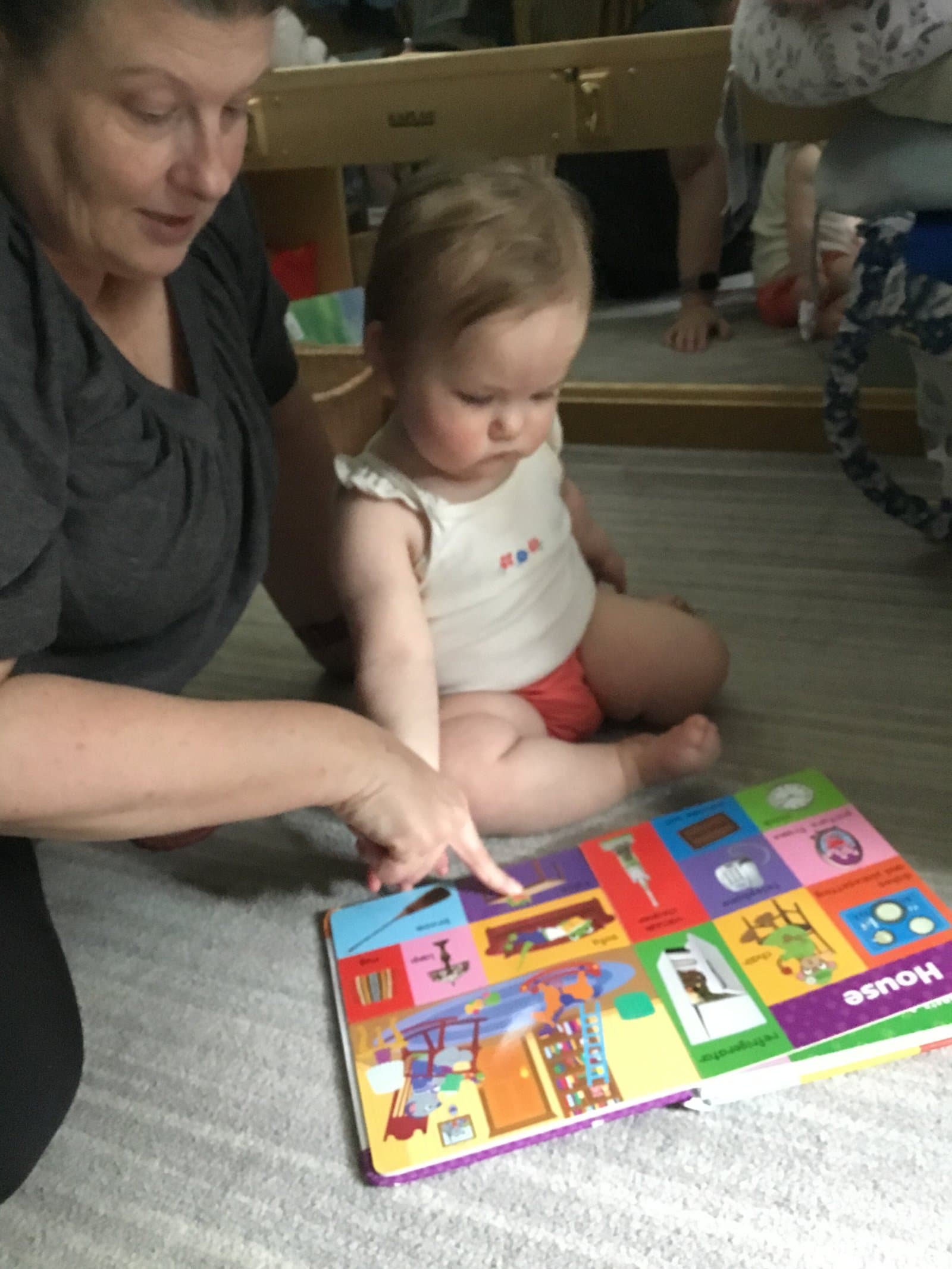 Little Acorns nursery teacher reading a book with an infant