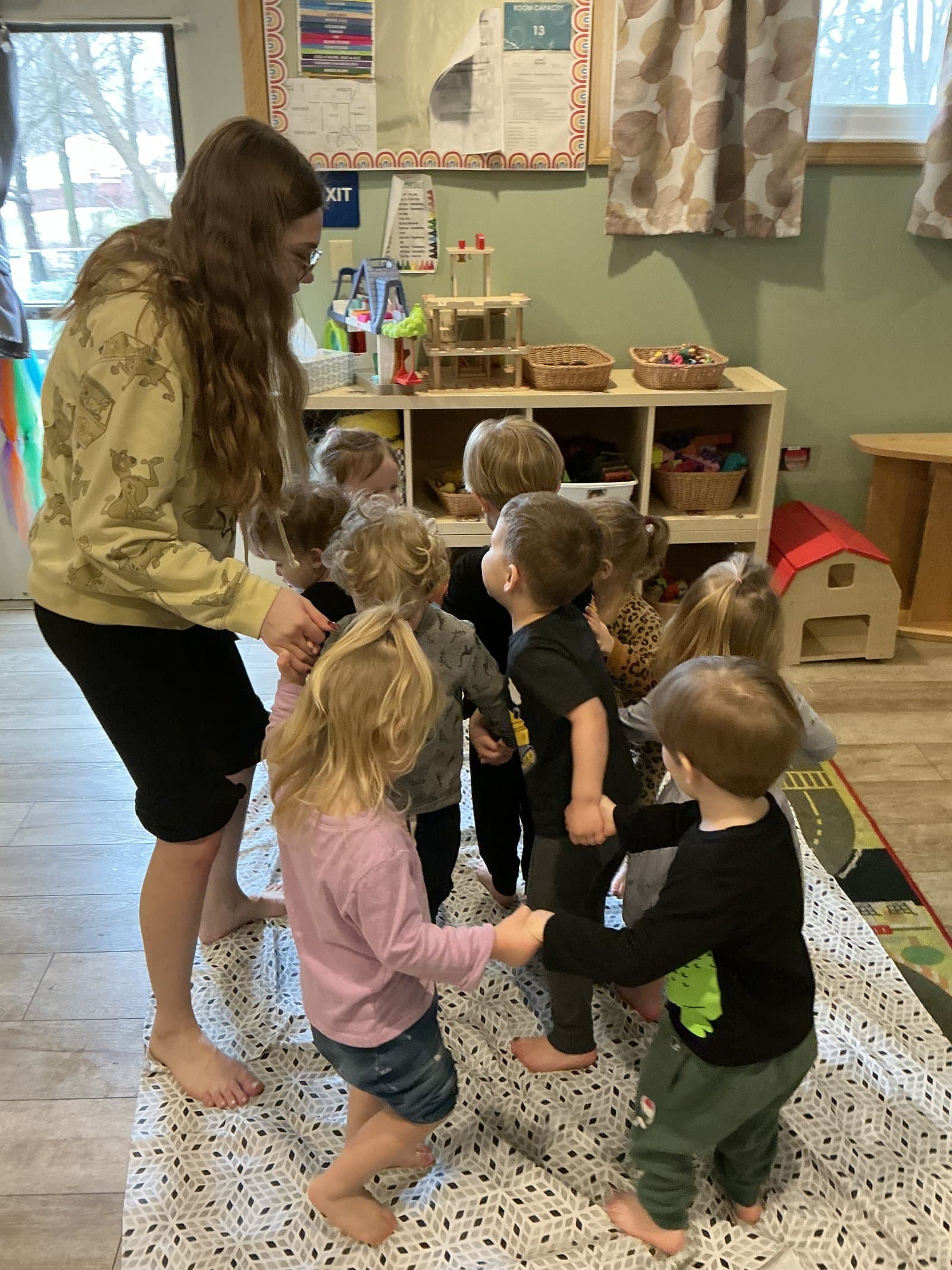 Little Acorns teacher engaging with a small group of toddlers in the classroom